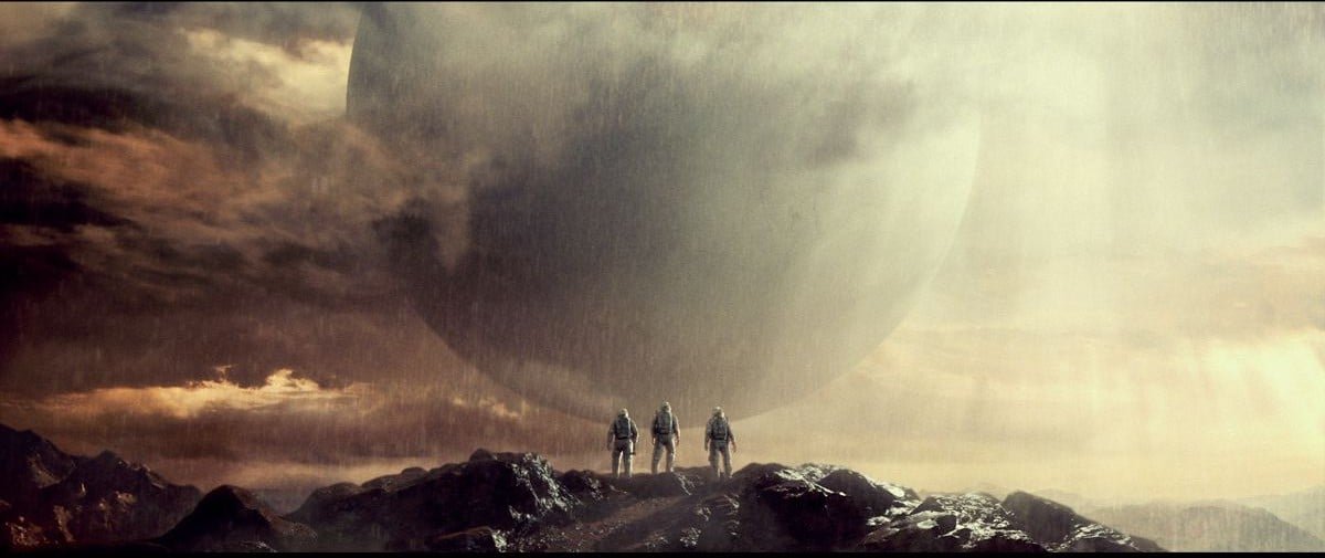 Trois astronautes sur une crête, face à une immense sphère dans la brume
